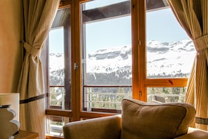 A room with a large window, a chair, and a lamp.