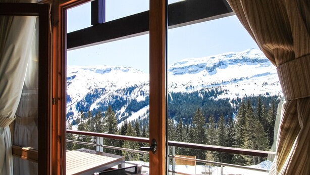 A room with a large window overlooking a snowy mountain landscape.