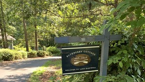 Un cartello di legno con la scritta "Blueberry Cottage" e "Benvenuti al Lago Hartwell", che indica il nome di una struttura e la sua posizione.