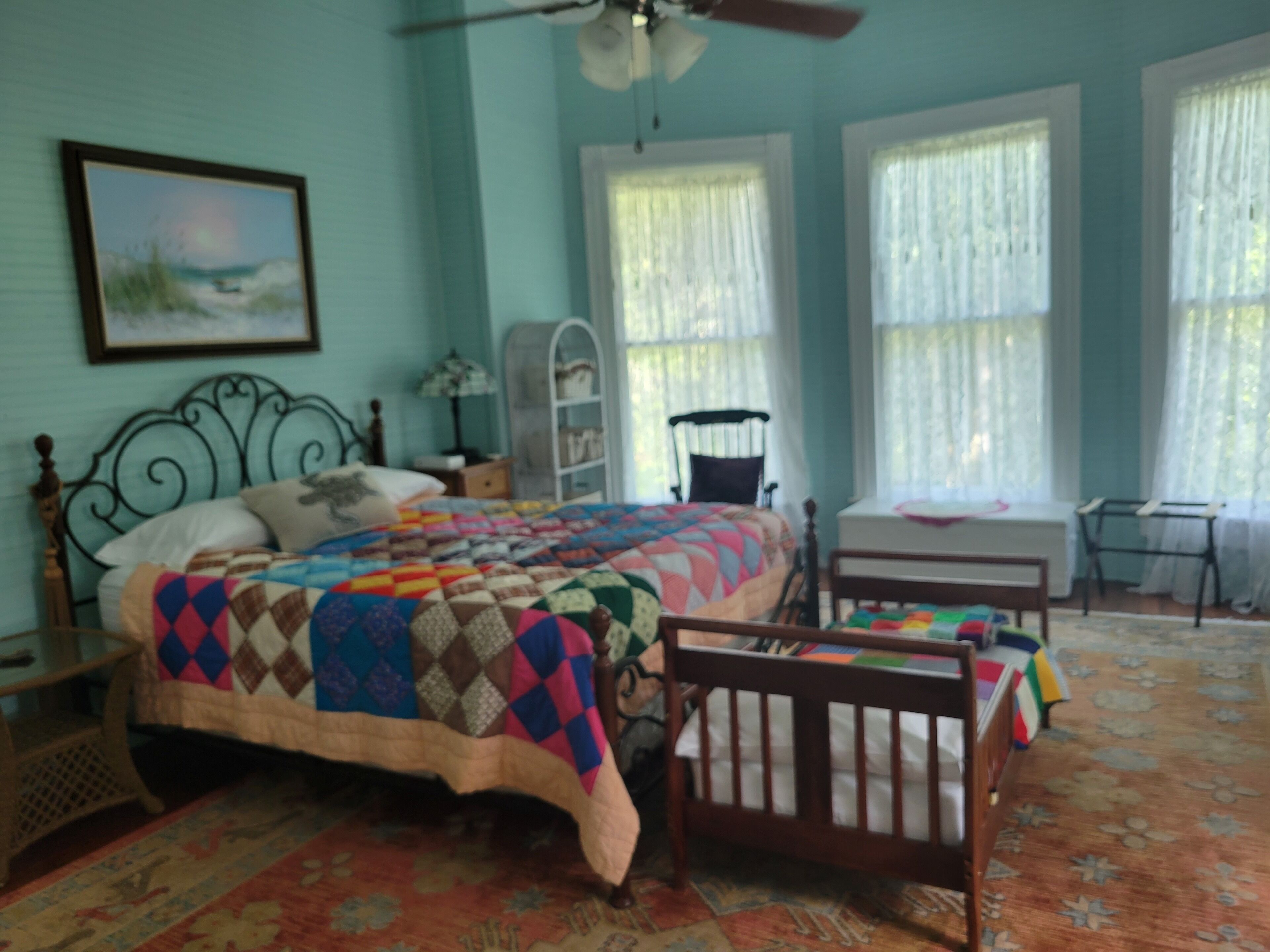 A bedroom with a bed, a crib, a desk, and a chair.