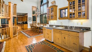 A spacious kitchen with wooden cabinets, a dining area with a large table, and a view of the outdoors through a window.