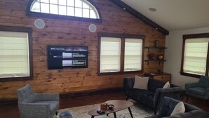 Ein gemütliches Wohnzimmer mit Holzwänden, einem großen Fenster und einem flachbildfernseher an der Wand.