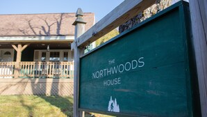 Et træskilt med teksten "The Northwoods House" og en silhuet af træer.