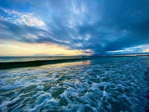 Une plage avec des vagues et un ciel nuageux.