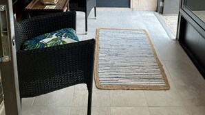 Una habitación con un mural con motivos playeros, muebles de mimbre, una lámpara y un tapete.