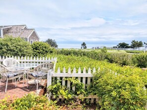 A patio with wicker furniture and a white picket fence.
