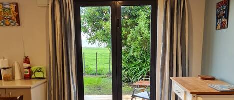 A dining area with a table, chairs, and a view through a glass door to an outdoor deck.