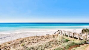 Ein Strand mit einer Holzpromenade, die zum Ufer führt.
