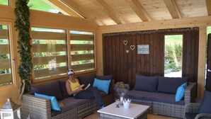 A cozy room with wicker furniture, wooden beams, and large windows. - Apartment Ariel by Interhome (Saanenmöser)