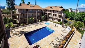 A hotel with a swimming pool, outdoor seating, and a view of the surrounding landscape. - Beachside Maui condo - pool & hot tub (Kihei)