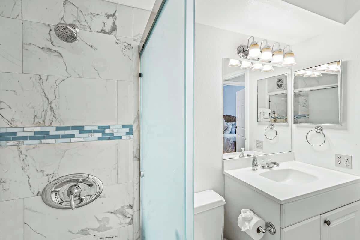 Ein Badezimmer mit Dusche, Waschbecken und Spiegel.