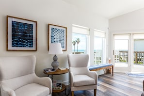 Relax in a serene space with a reading nook, artworks, and a balcony overlooking palm trees.