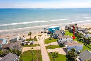 A coastal residential area with houses, a beach, and a clear view of the ocean.