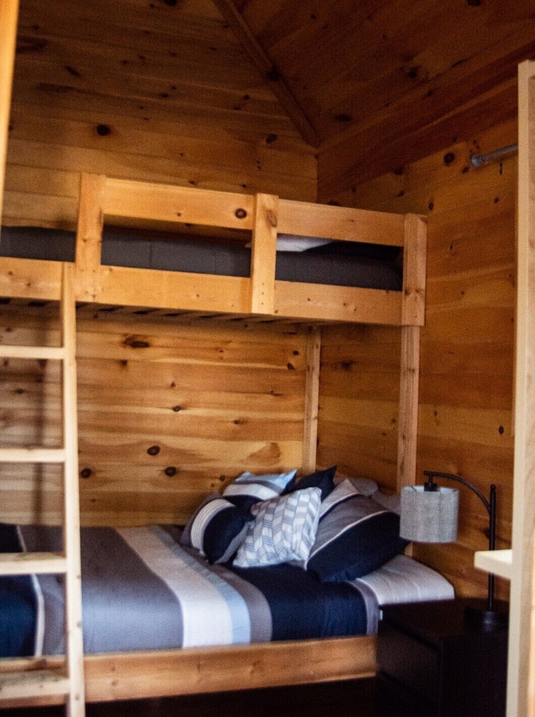 A bunk bed with a ladder, a bedside table, and a lamp.