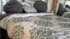 Uma cama com colcha estampada, travesseiros e cabeceira.