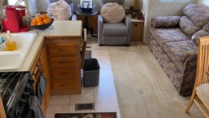 Cozinha compacta de um veículo recreativo, com armários de madeira, fogão e pia.