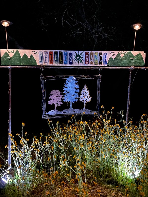 A decorative sign with trees and a swing, surrounded by yellow flowers.