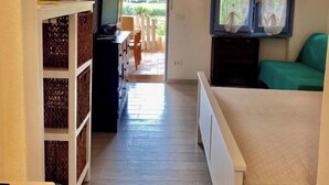 A hallway with a bed, a TV, and a window with curtains. - Portolano - Portolano 6 (Porto Azzurro)