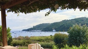 A coastal view with boats, greenery, and a hill in the background. - Portolano - Portolano 6 (Porto Azzurro)