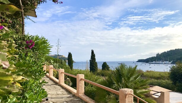 A stone staircase leading to a terrace overlooking a coastal view with boats and greenery. - Portolano - Portolano 6 (Porto Azzurro)