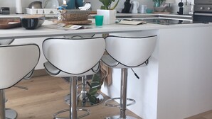 A modern kitchen with wooden cabinets, a central island with bar stools, and various kitchen appliances.