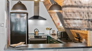 Eine Küche mit modernem Herd, Backofen und Mikrowelle unter einer geneigten Decke mit freiliegenden Holzbalken.