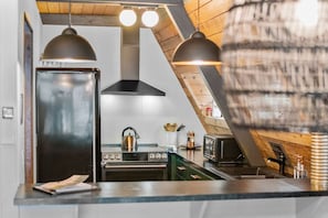 Eine Küche mit modernem Herd, Backofen und Mikrowelle unter einer geneigten Decke mit freiliegenden Holzbalken.