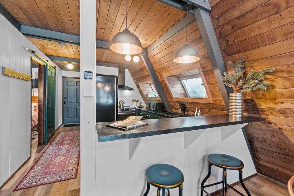 A modern kitchen with a central island, pendant lighting, and a view of the outdoors.