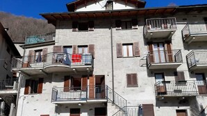 Um edifício com várias andares, varandas, uma escadaria e uma porta vermelha.
