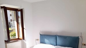 Quarto com uma cama, janela e radiador.