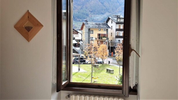 Quarto com janela com vista para uma montanha e uma cidade.