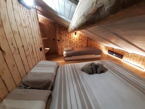 A cozy attic bedroom with wooden walls, a bunk bed, and a single bed. - Dream house four-leaf clover. (Folgarida)