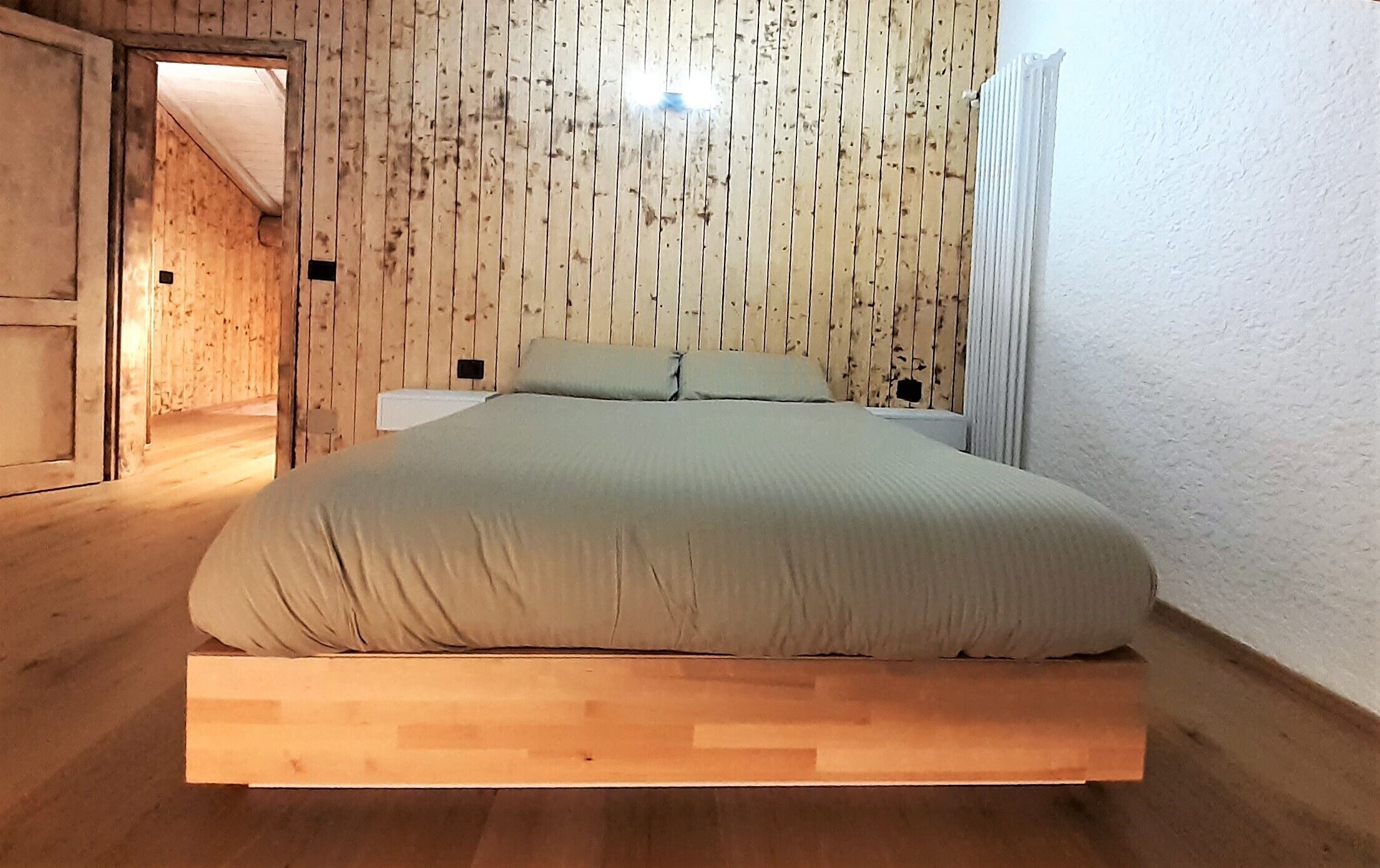 Un lit avec un cadre en bois et une tête de lit faite de lattes de bois verticales.
