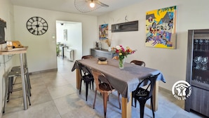 A dining area with a table, chairs, a clock, and artwork on the walls. - "Charming Cottage with Private Observatory, Terrace & Garden in Origné" (Origne)