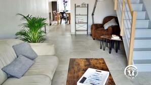 A modern living room with a sofa, coffee table, and a staircase. - "Charming Cottage with Private Observatory, Terrace & Garden in Origné" (Origne)