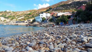 A rocky beach with buildings in the background. - "CASA POMONTE" ON THE SEA with PRIVATE PARKING SPACE. (Pomonte)