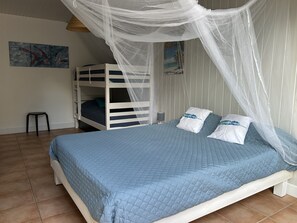 Un dormitorio con una cama litera, una cama con dosel, una mesita pequeña y una obra de arte en la pared.