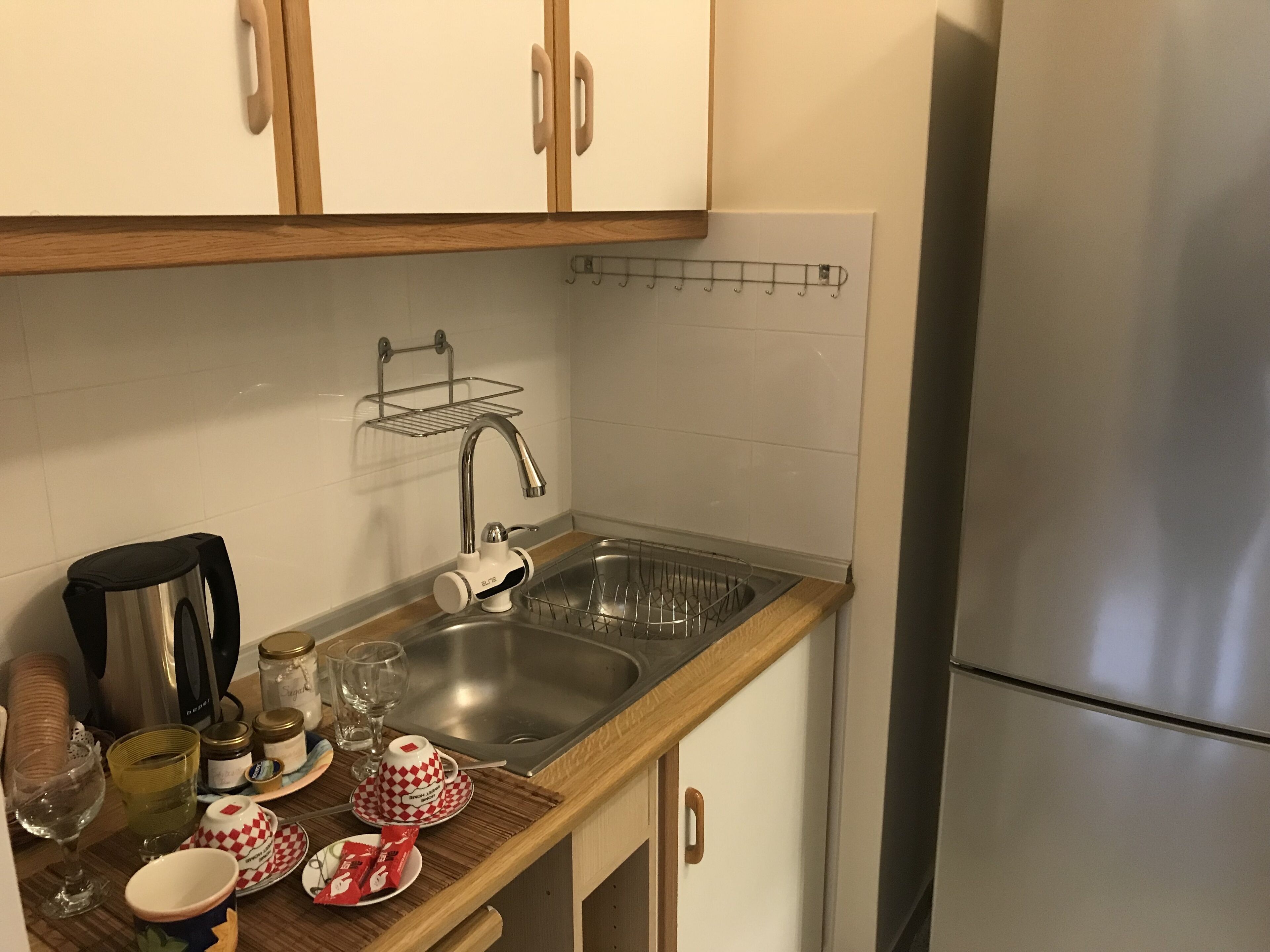 Een kleine keuken met een roestvrijstalen spoelbak, een waterkoker en een koelkast.