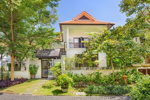A two-story house with a tiled roof, a balcony, and a garden with various plants and a small pond. - Abogo Resort Villas Luxury Da Nang (Da Nang)