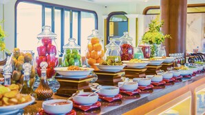 A buffet with various food items in glass containers and bowls, arranged on a counter with a view of a train through the window.