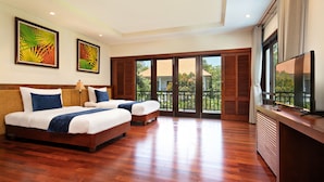 A hotel room with two beds, a TV, and a balcony with a view.