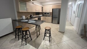 A modern kitchen with a central island, stools, and a refrigerator.