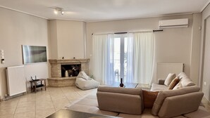 A modern living room with a fireplace, a sofa, a coffee table, and a view of the outdoors.