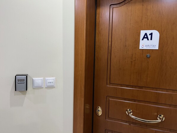 Una puerta de madera con un letrero que dice 'A1 AIRSTAY' y un teclado de bloqueo en la pared.