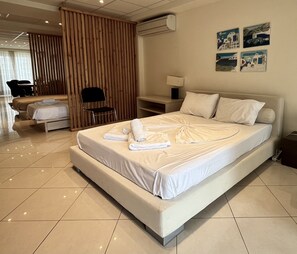 Quarto de hotel moderno com uma cama grande, um painel de madeira, uma escrivaninha e uma cadeira.