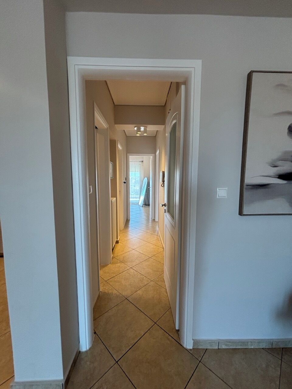 A hallway with a tiled floor leading to a door at the end.