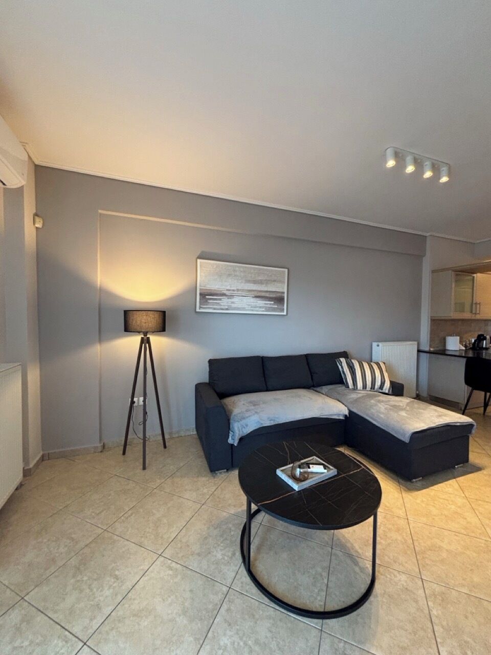 A modern living room with a sofa, a coffee table, a floor lamp, and a painting on the wall.