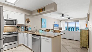 A modern kitchen with white cabinets, stainless steel appliances, and a large island. - ETW 3001: Cozy Cove - Gulf of Mexico Tides... Nature’s Perfect Rhythm (Fort Walton Beach)