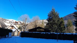 Una calle cubierta de nieve con casas y una montaña al fondo.