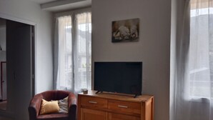 Una habitación con un armario de madera, un sillón de cuero, un televisor de pantalla plana y un cuadro en la pared.